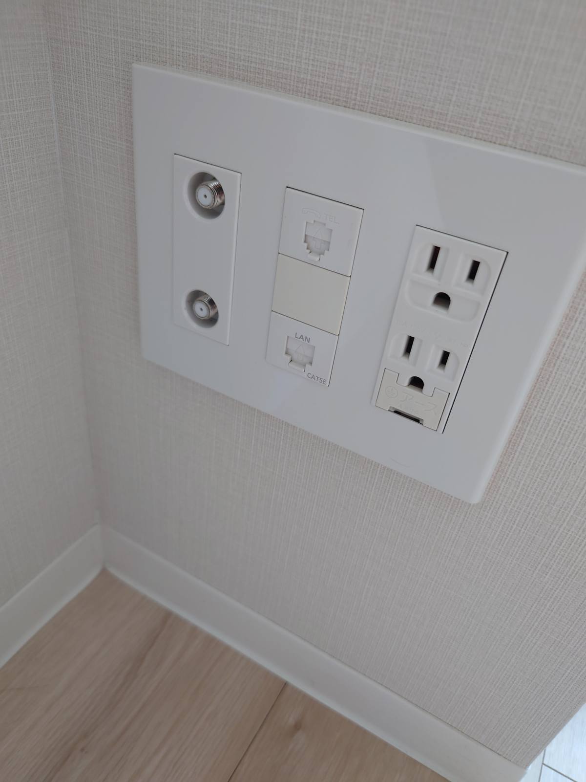 壁のマルチメディアコンセント。TV端子が2つ、電話の端子、LAN端子(CAT5E)、電源が2口。光コンセントは無い